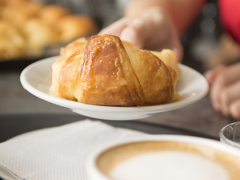 close up waitress s hand offering baked croissant