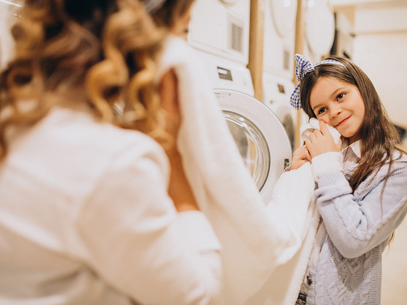 mother with daughter doing laundry self serviece laundrette